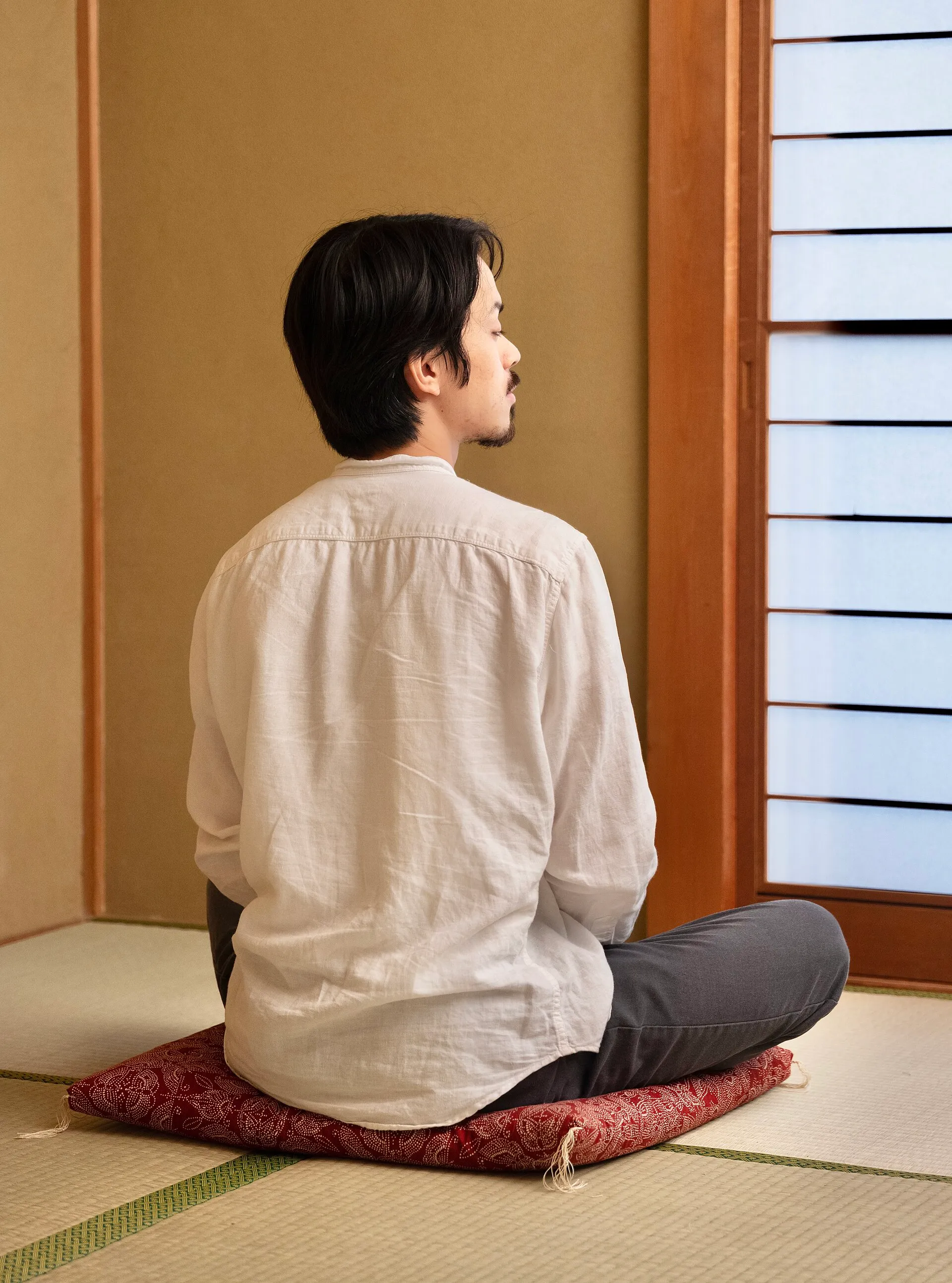 A practitioner sitting zazen on a round cushion in a quiet room